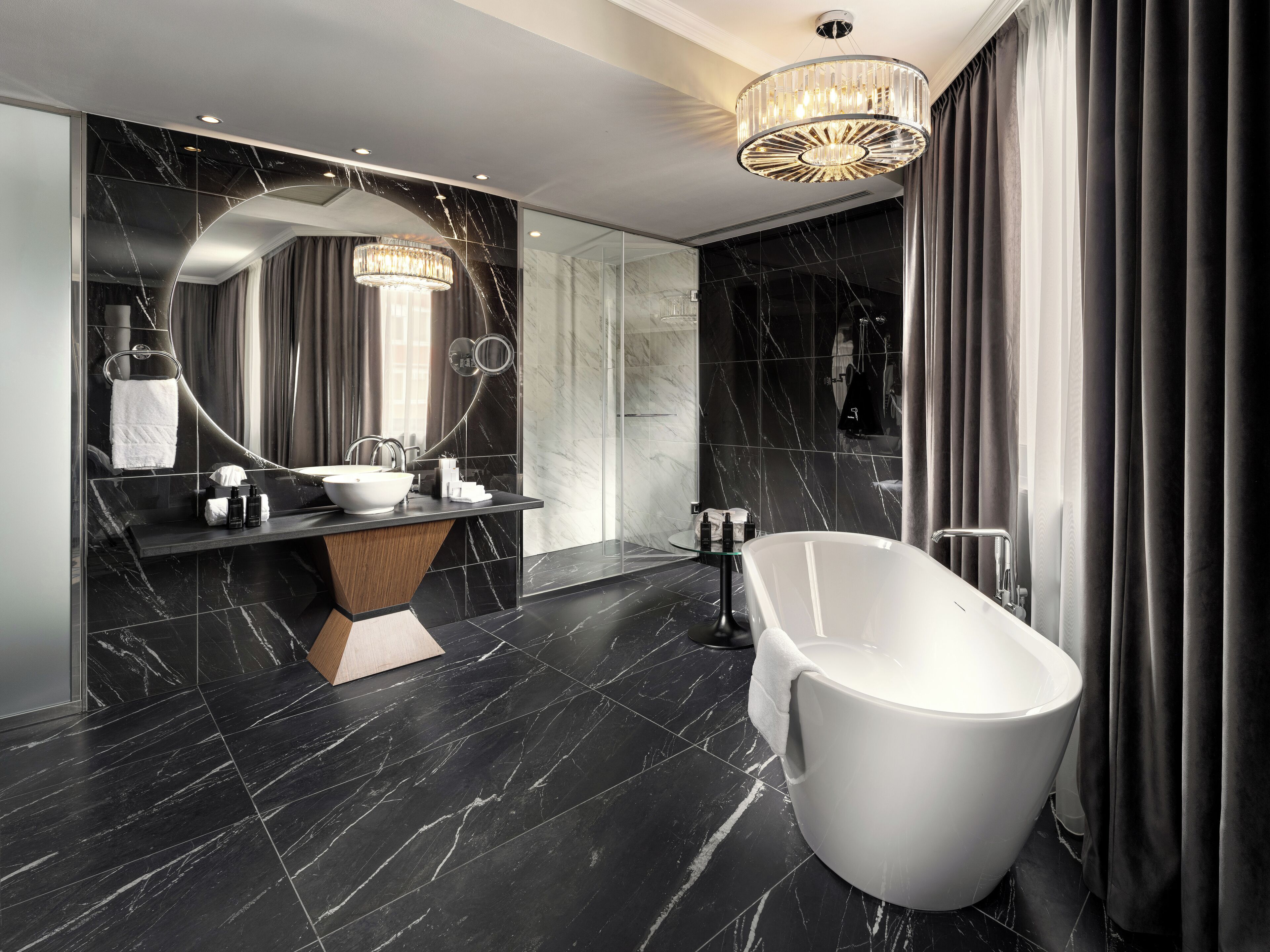 A modern bathroom with a freestanding bathtub, a vanity with a marble countertop, and a large mirror.