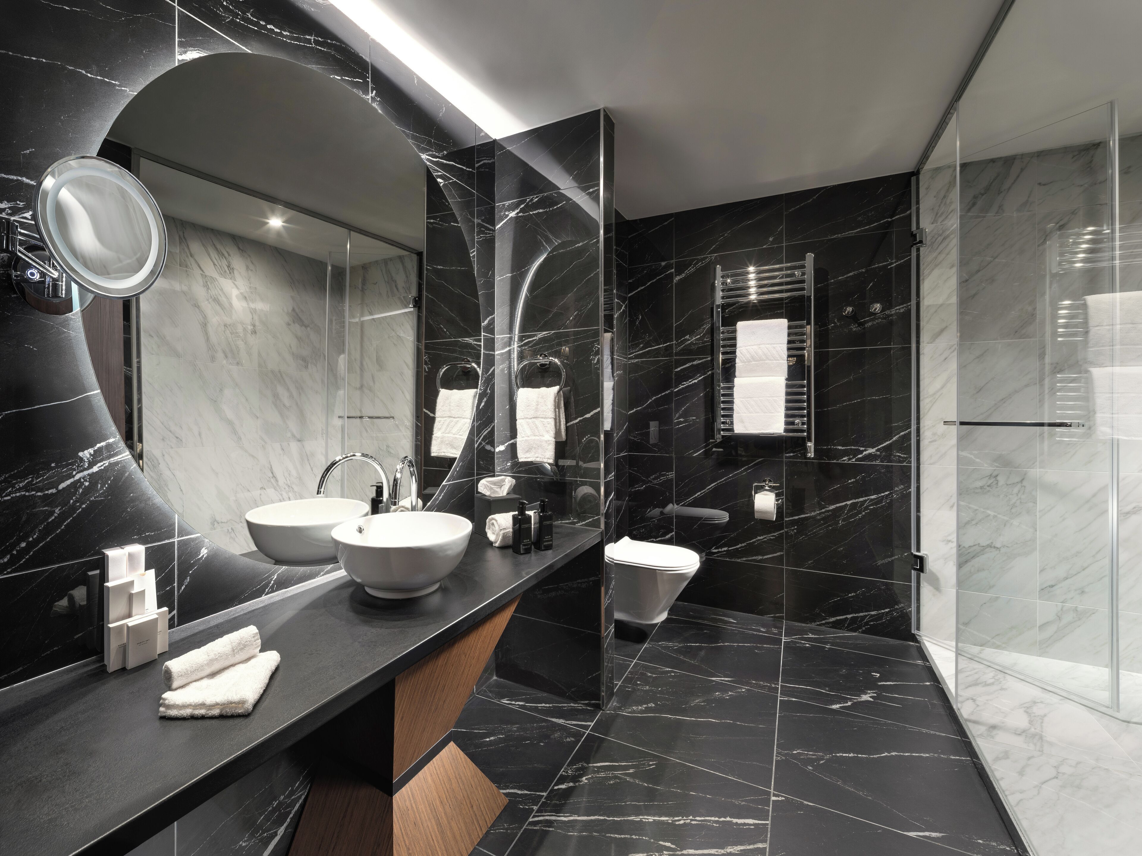 A modern bathroom with two sinks, a large mirror, and a glass shower enclosure.