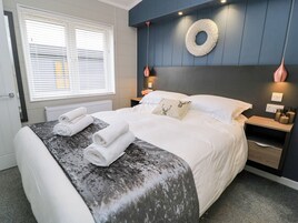 Un dormitorio moderno con cama, mesita de noche, lámpara de pared y ventana con persianas.