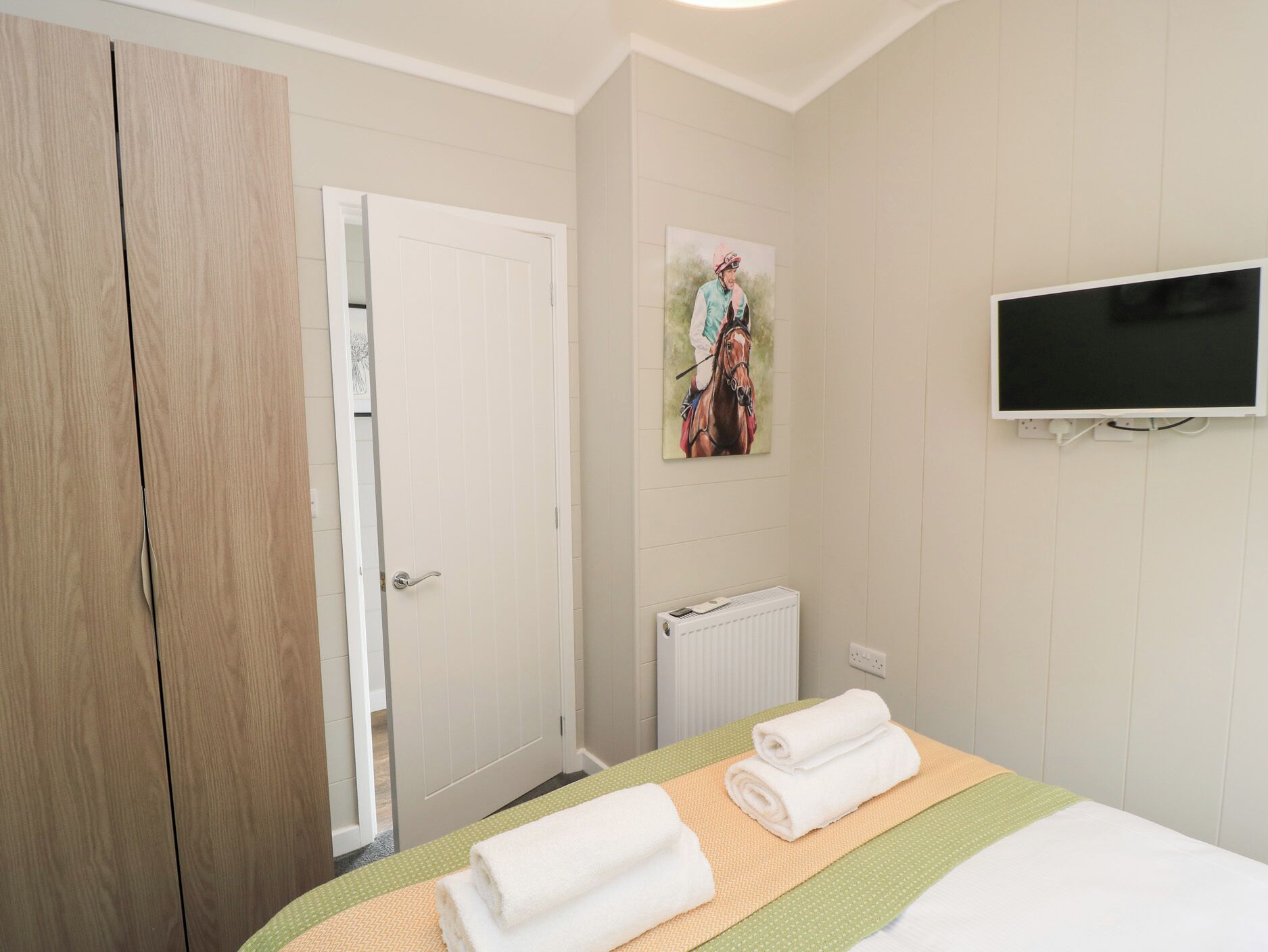 Una habitación de hotel con una cama, un cuadro, un televisor y un radiador.