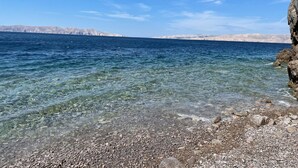 Une vue dégagée sur la côte, avec un rivage rocheux et des montagnes à l’horizon.