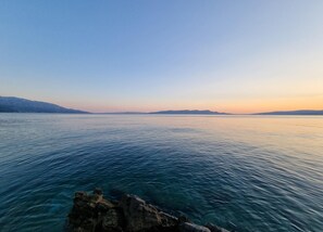 A calm body of water with distant landforms, clear skies, and rocky formations at the foreground. - Apartment in Croatia Near Adriatic Coast (Senj)