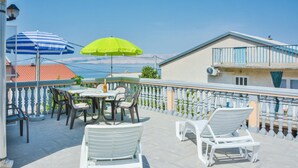 Un balcon avec un espace salon extérieur, une table et deux parasols.