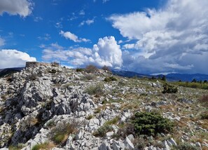 A rocky landscape with a stone structure on a hill, under a partly cloudy sky. - Apartment in Croatia Near Adriatic Coast (Senj)