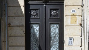 A black double door with ornate glass panels, a stone facade, and a number plaque. - Charming Central Porto Apartment (Porto)