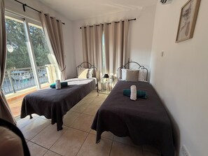 A hotel room with two beds, a balcony, and a view of the outside.