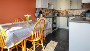 A kitchen with white cabinets, a tiled backsplash, and a dining area with a table set for two.