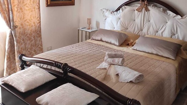 Ein Schlafzimmer mit einem hölzernen Bett, einem Nachttisch, einem gerahmten Gemälde und einer Wand-Klimaanlage.
