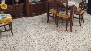 Ein Essbereich mit Holztisch und Stühlen, einem Schrank mit Glastüren und einem Fliesenboden.
