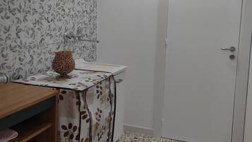 Un bany amb terra de rajola, un penjador de fusta amb mirall, un rentapeus i un vas decoratiu.