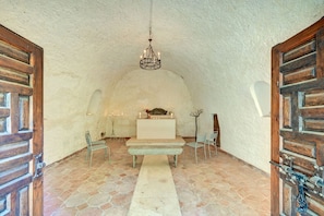 Ein gewölbter Raum mit einem weißen Altar, Bänken und Stühlen.