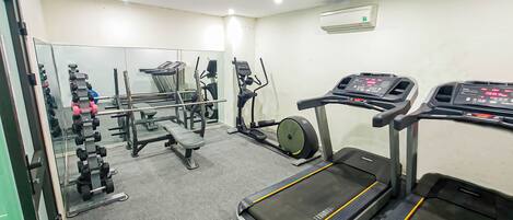 A gym with treadmills, a bench press, and a mirror.