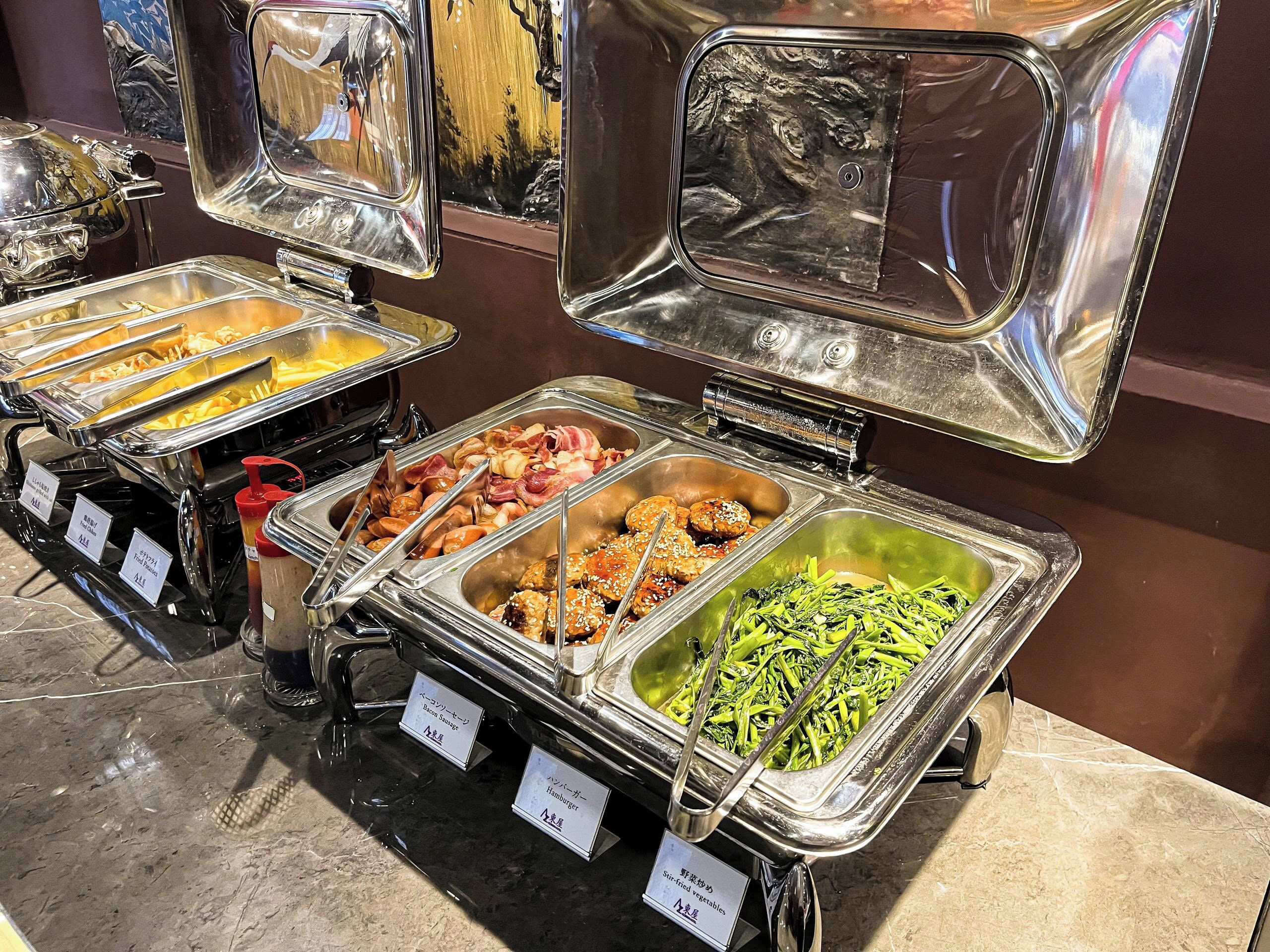 A buffet with various food options including meats, vegetables, and sauces.