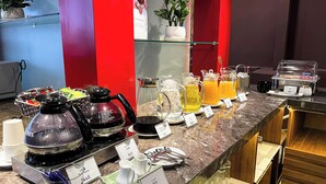 Un bufé de desayuno con diversas bebidas y platos, como café, té y leche.