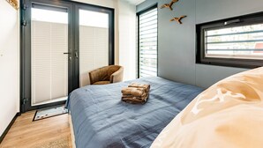 A bedroom with a bed, a chair, a window, and a door. - Hausboot am Prerauer Stich in Zehdenick (Zehdenick)