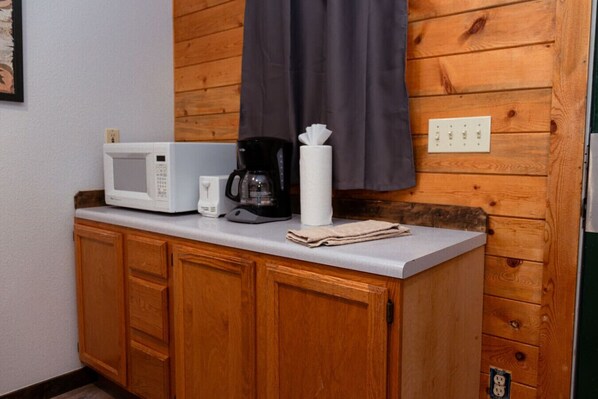 A kitchenette with a microwave, coffee maker, and a towel on the counter.