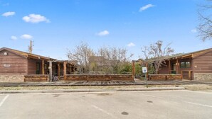 Ein rustikales Holzhaus mit überdachter Veranda und einem kleinen Parkplatz davor.