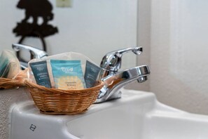 En vask med en kurv i fletværk, der indeholder tre shampoo flasker.