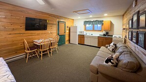 Een compacte wooneenheid met een eethoek, kitchenette en een bank met een hond.