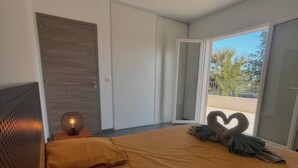 A modern bedroom with a large bed, a ceiling fan, and a view through a sliding glass door. - Villa Melendria, Ghisonnaccia (Ghisonaccia)