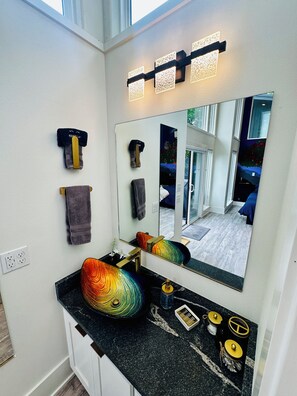 A bathroom with a black countertop, a mirror, and a towel rack. - Firefly 2, luxury lakeside treehouse w/ hot tub, BBQ, extra parking, boat put-in (Eureka Springs)