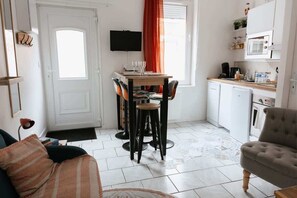 Cozy living space with a dining area, TV, kitchenette, and sofa.