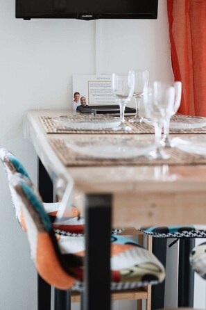 Enjoy meals in this cozy dining area with a table for two, featuring a placemat and menu card, and a TV mounted on the wall.