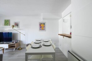 Enjoy meals together at the dining table for four, accompanied by a TV on a nearby stand.