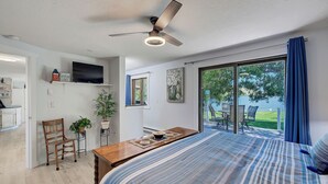 A bedroom with a bed, a desk, chairs, a television, and a view of the outdoors. - Lakefront single story house on Hauser Lake (Helena)