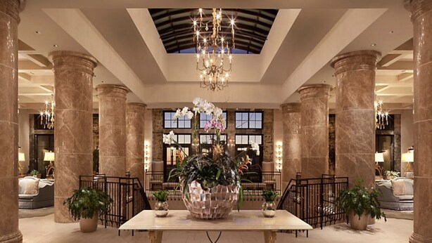 A lobby with marble columns, a chandelier, and a large floral arrangement.