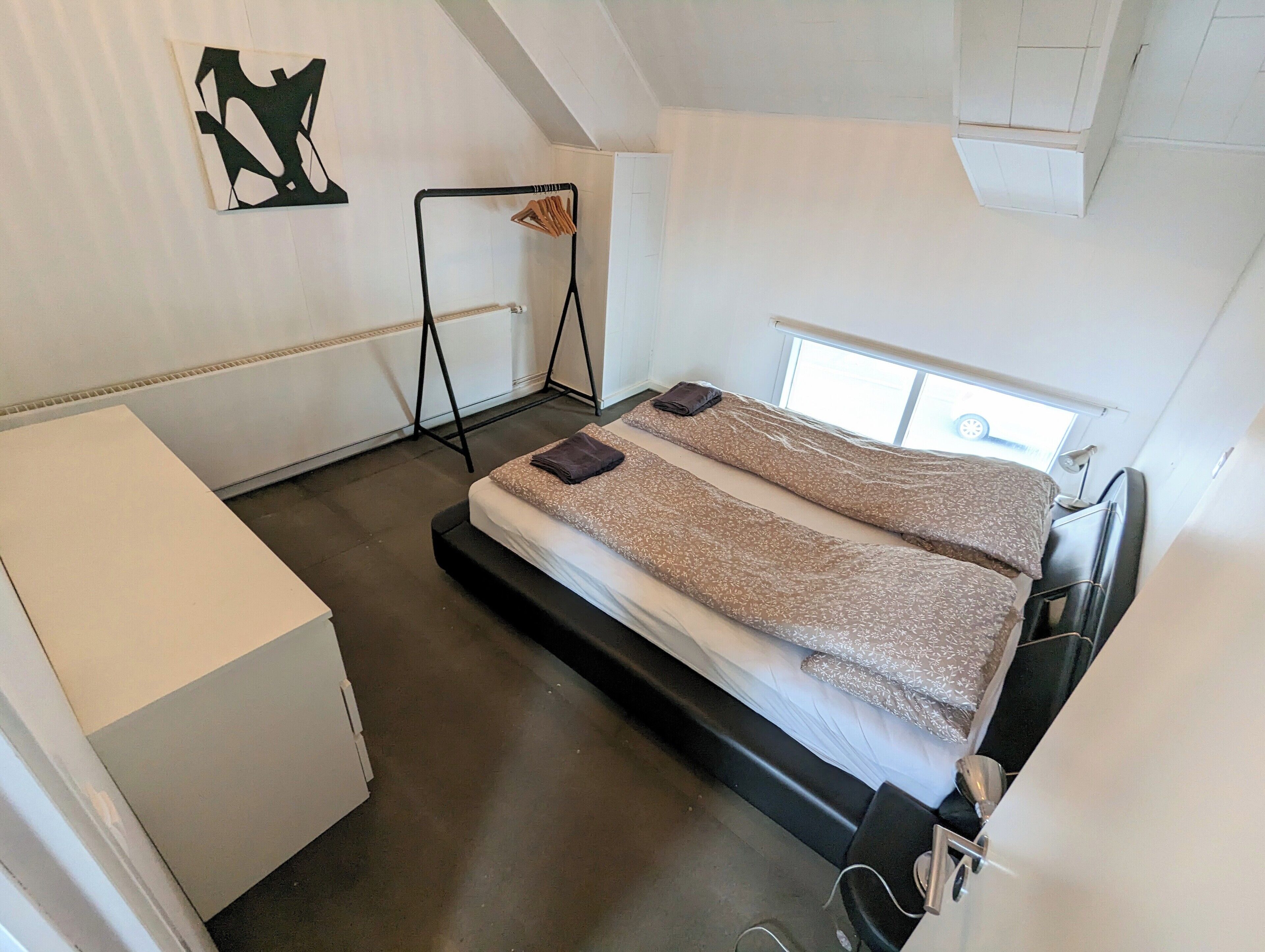 A compact room with a bed, a small desk, and a radiator.