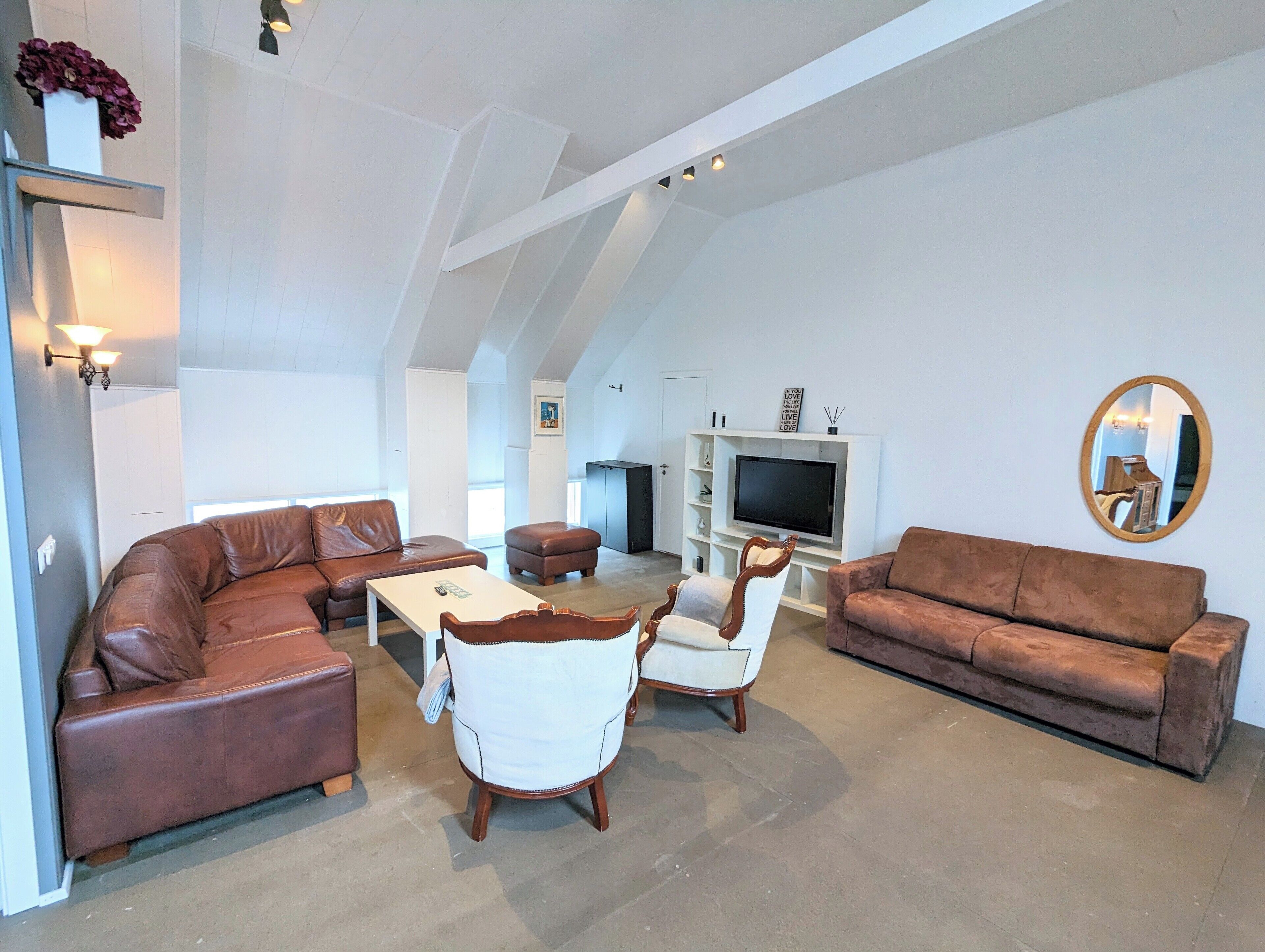 A spacious living room with a high ceiling, a television, and a fireplace.