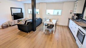 A modern apartment with a living room, dining area, kitchen, and a large window. - Central Apartments  (Vestmannaeyjar)
