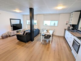 Un apartamento moderno con sala de estar, comedor, cocina y un gran ventanal.