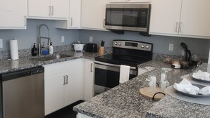 A modern kitchen with white cabinets, a stainless steel microwave, a stove, and granite countertops. - 4 Downtown Indy SkyWalk to Gainbridge Lucas Oil Conv Cntr (Indianapolis)