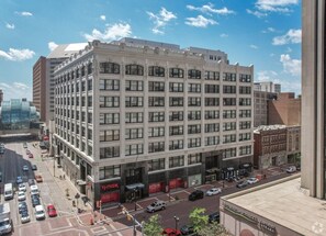 A multi-story building with a classic architectural style, featuring a central entrance with a red awning and several ground-level commercial spaces. - #4 Downtown Free Parking- Walk to Lucas Oil, Conv Center, Gainbridge (Indianapolis)