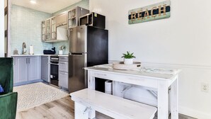 A modern kitchen with grey cabinets, a stainless steel refrigerator, and a white countertop.