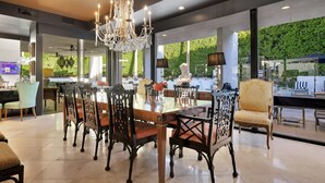 A spacious dining area with a large wooden table, ornate chairs, and a chandelier.