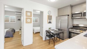 A compact kitchen with a refrigerator, microwave, and stove. There is a dining table with chairs and a small clock on the wall. - @Marbella Lane - Serene Haven Retreat (Ontario)