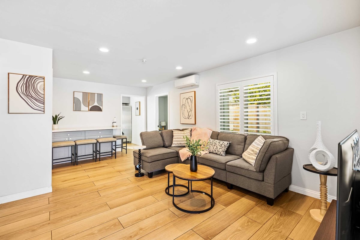 A modern living room with a grey sofa, a round coffee table, and a TV on a wooden stand.