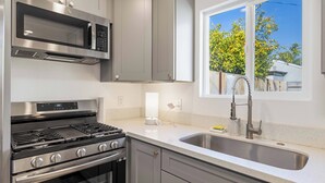 A kitchen with stainless steel appliances, a double sink, and a window with a view of trees. - @Marbella Lane - Serene Haven Retreat (Ontario)