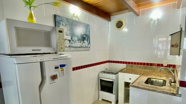A compact kitchen with a refrigerator, microwave, stove, and sink.