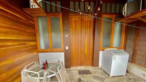 A wooden cabin with a stone floor, a table with chairs, and a washing machine.
