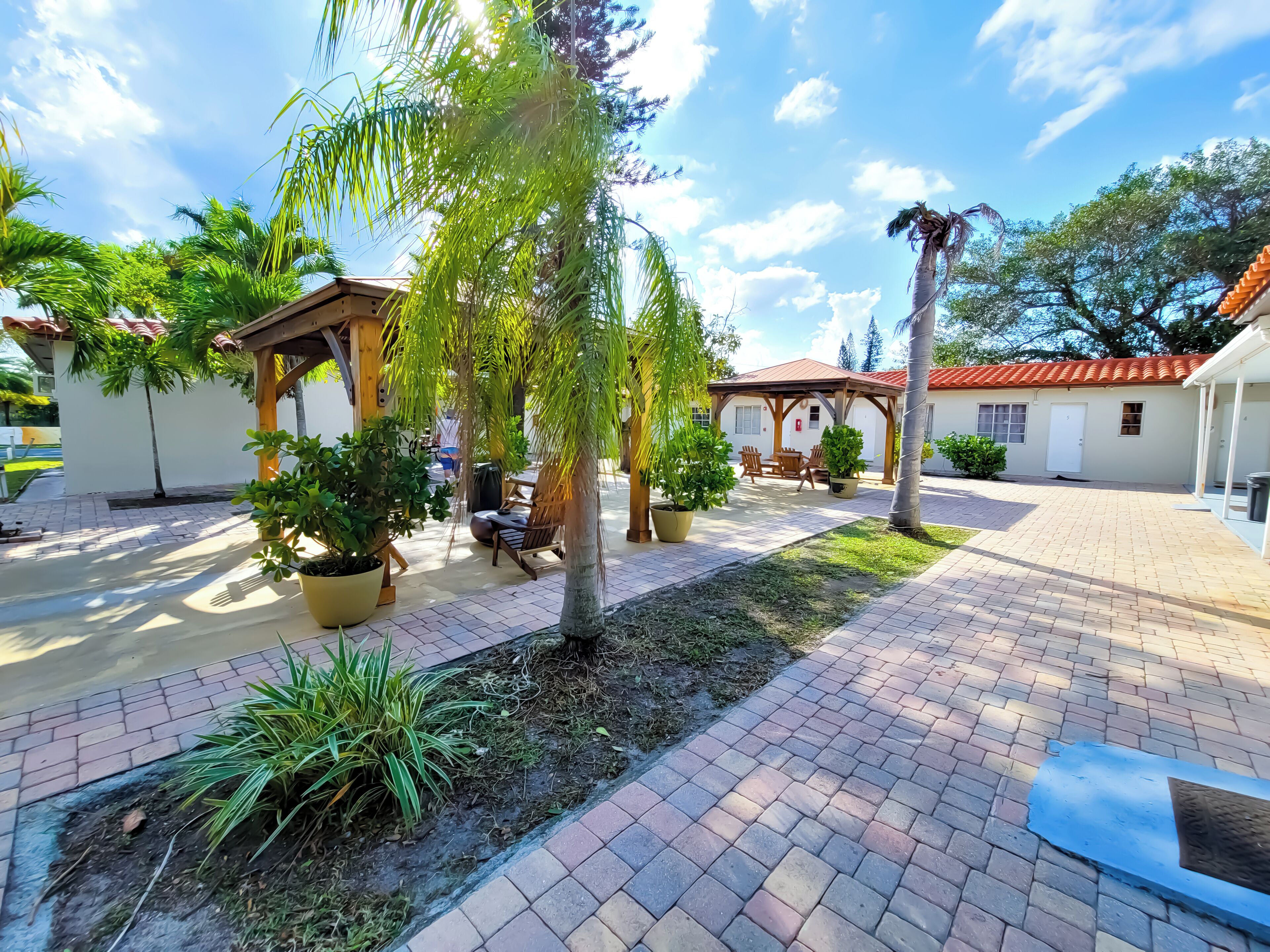 A courtyard with a pergola, seating area, and potted plants.
