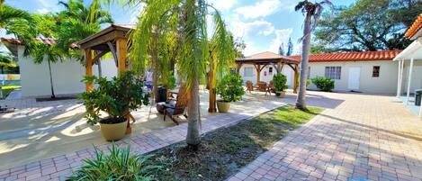 A courtyard with a pergola, seating area, and potted plants.