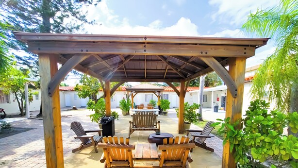 A covered outdoor seating area with wooden furniture and potted plants.