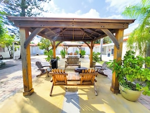 A covered outdoor seating area with wooden furniture and potted plants. - Stay Inn Boutique Hotel  (Dania Beach)
