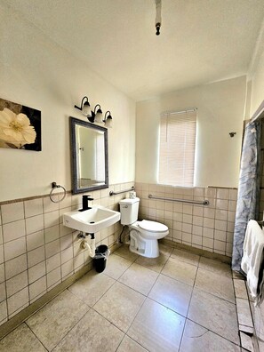 A bathroom with a sink, toilet, and mirror. - Stay Inn Boutique Hotel  (Dania Beach)