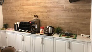 A kitchen with white cabinets, a coffee maker, a kettle, and a toaster on the countertop.