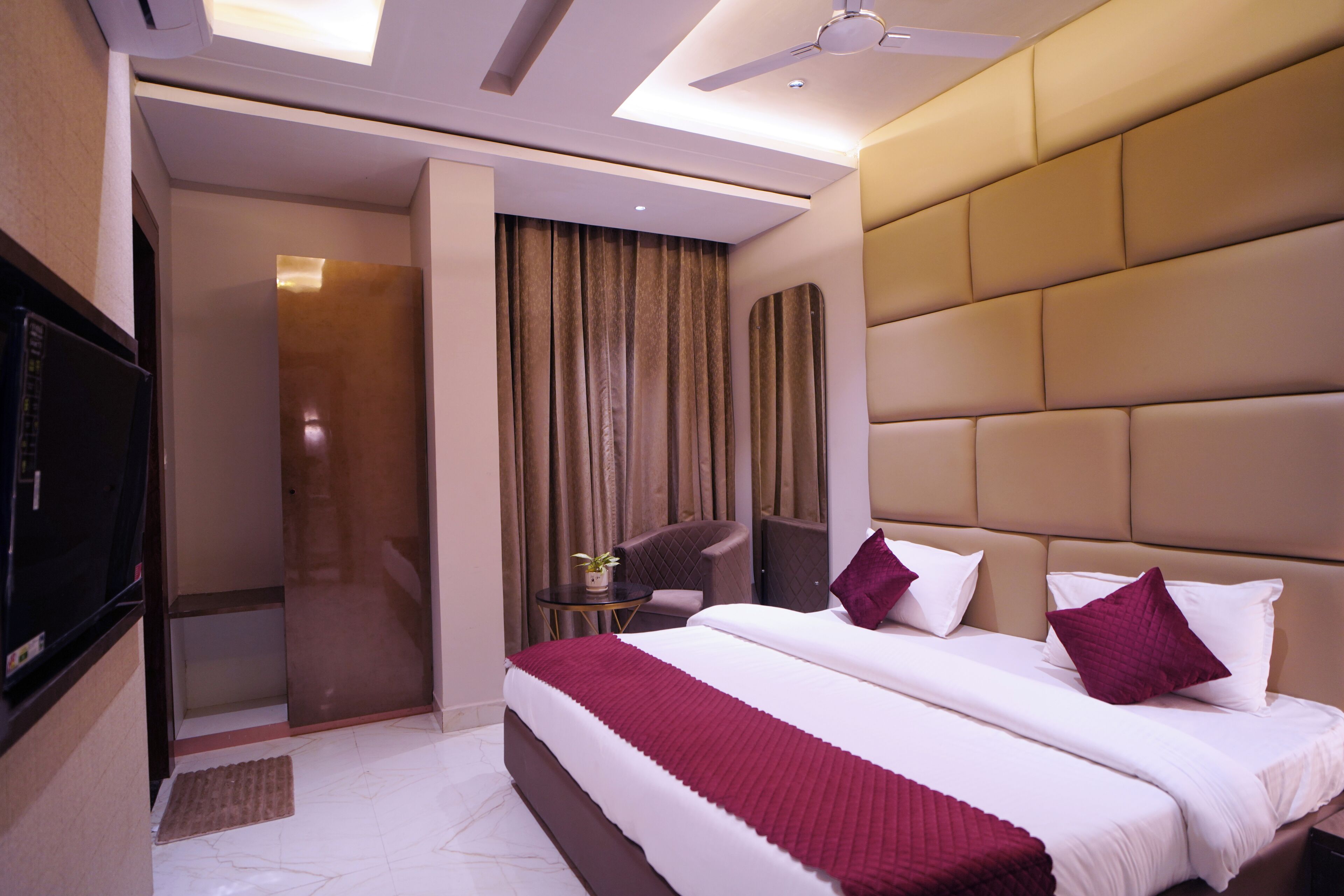 A modern hotel room with a large bed, a TV, a seating area, and a shower.